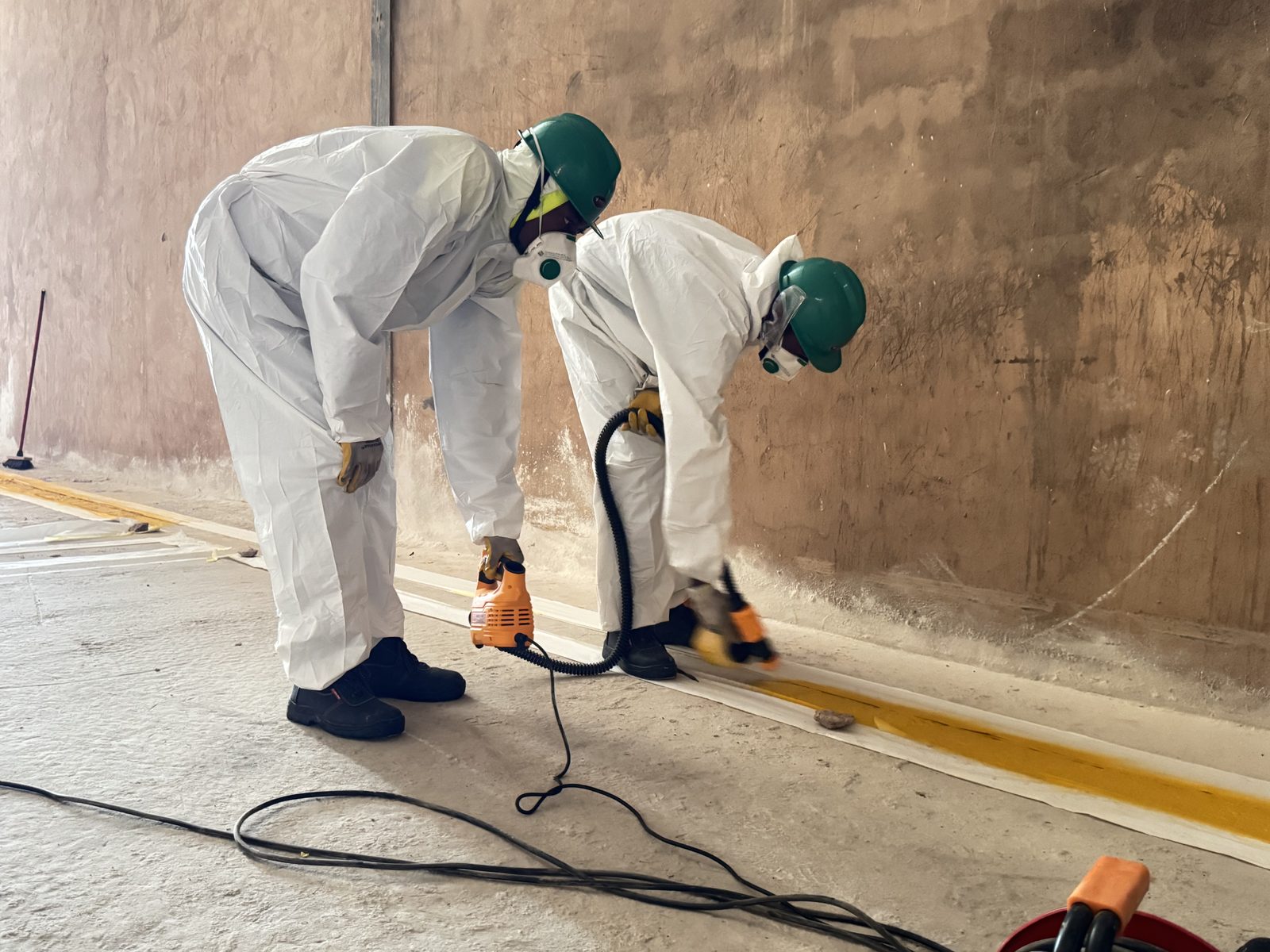 Ubuntu Groupe technicians applying industrial floor sealant in protective gear
